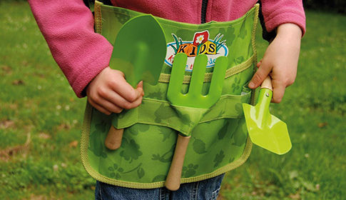 Enfant avec un tablier de jardinier et de petits outils