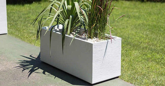 Jardinière rectangulaire blanche sur le bord d'une terrasse