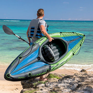 Homme avec un kayak gonflable sur une plage