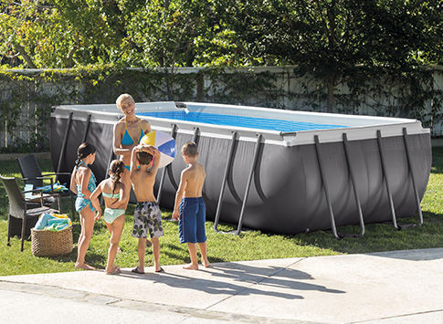 Piscine rectangulaire grise avec 1 adulte et 4 enfants devant la piscine