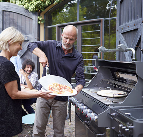 Service d'une pizza cuite dans un barbecue à gaz