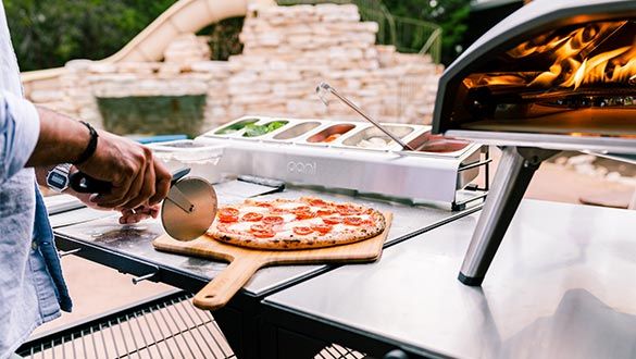Pizza en train d'être découpée avec une roulette sur une planche