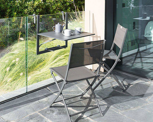 Table pliable pour balcon accrochée à une paroi en verre avec 2 chaises