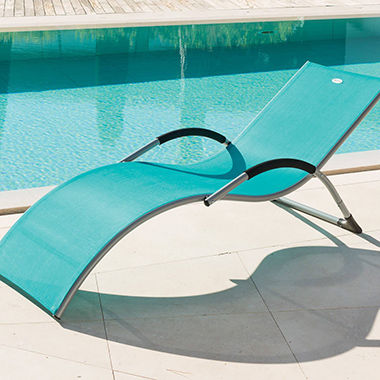 Chaise longue bleue non réglable au bord d'une piscine