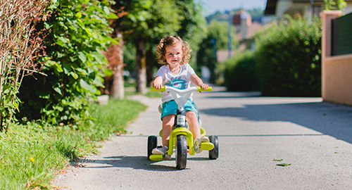 Petite fille sur un tricyle vert et blanc