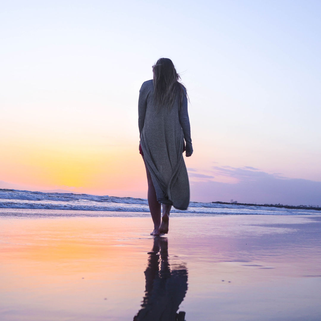 Person walking along the beach at sunset
