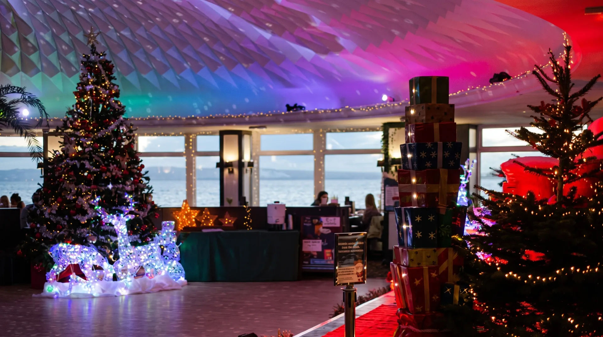 Decorated Christmas tree and illuminated reindeer with colourful gifts in a festive indoor setting