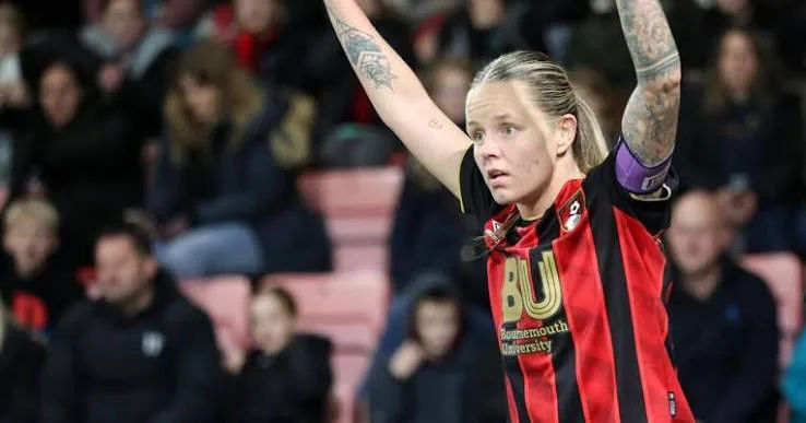 AFC Bournemouth player Katie James celebrating with arms raised during a match, wearing a red and black striped kit.