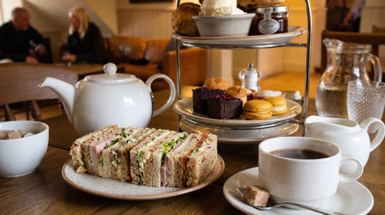 A selection of sandwiches, pastries, and tea at a café table