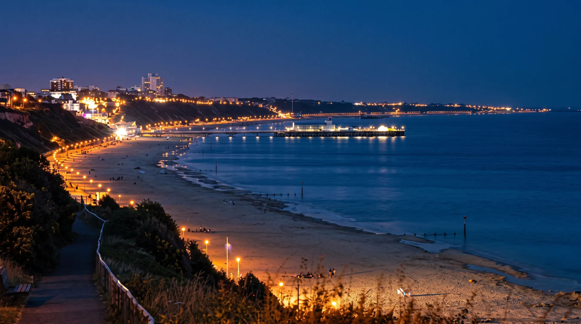 Night view of Southbourne beach with lights along the shore and pier reflecting on the water