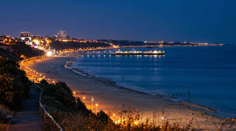 Bournemouth beach and pier lit up at night with city lights in the background