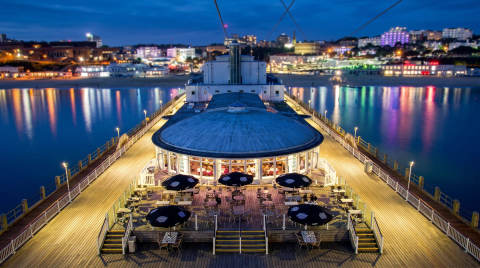 View of Bournemouth Pier with a restaurant and lights reflecting in the water