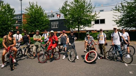A group of cyclists posing with their bikes outside a stadium