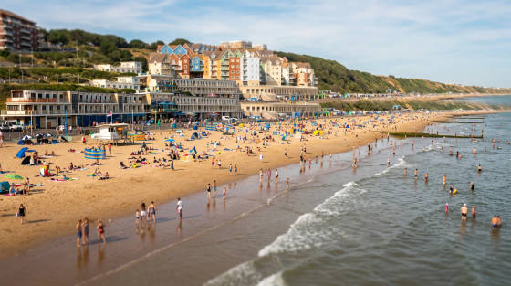 Crowded beach with sunbathers, swimmers and beach huts