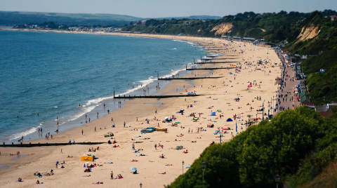 Crowded beach at Bournemouth with sunbathers and swimmers