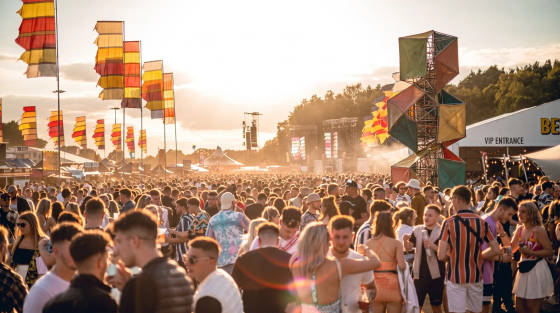 Large crowd enjoying a festival with flags and stages