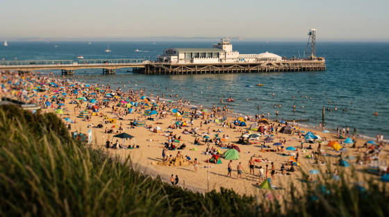 Crowded Bournemouth beach with colourful umbrellas and a pier