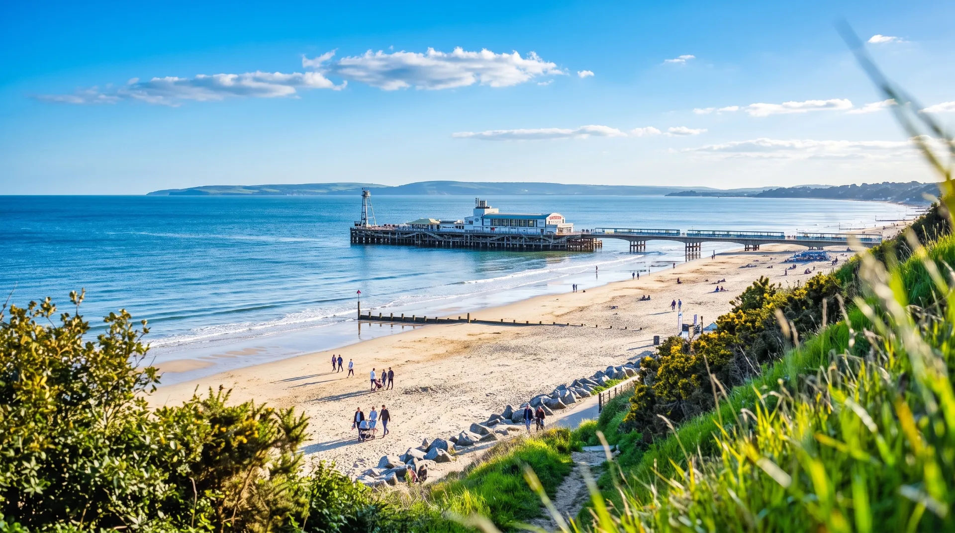 Bournemouth beach with people walking, pier in the background, and blue sky