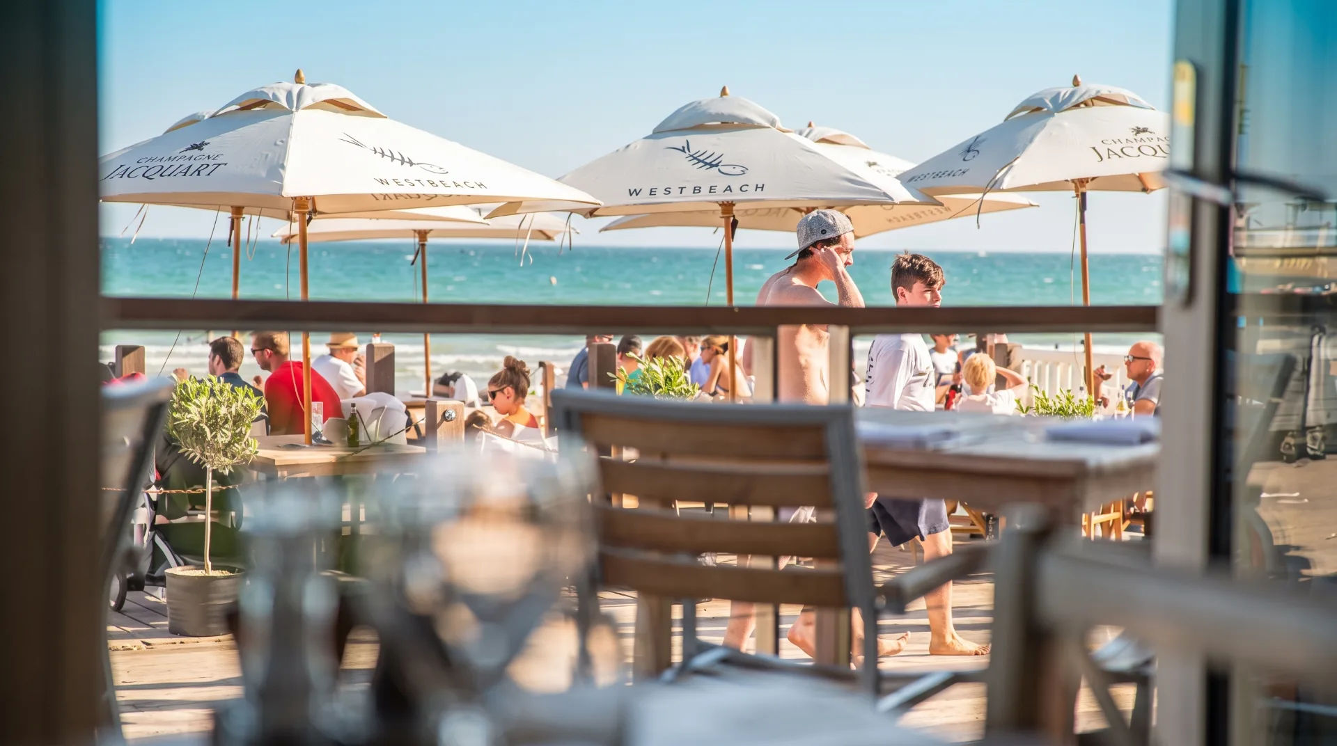 View of a bustling beachside restaurant with umbrellas and diners enjoying the seaside atmosphere