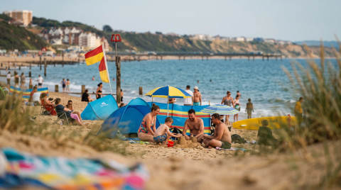 Families on Bournemouth beach with umbrellas and sandcastles