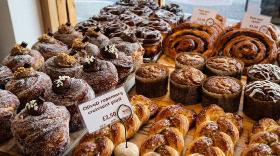Assorted pastries including croissants and muffins on a wooden table