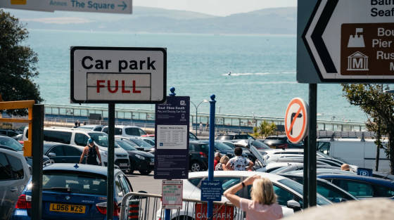 Sign indicating car park is full with the sea in the background
