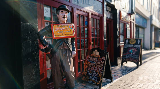 Statue of Charlie Chaplin with a sign outside a restaurant