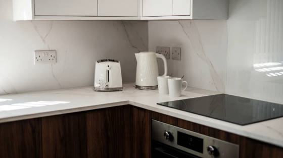 A white kettle and toaster on a marble kitchen countertop