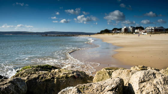 Rocky shoreline at Sandbanks Beach with calm sea and clouds