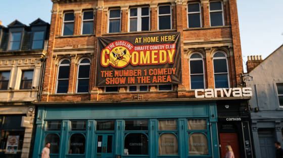 A large banner for The Giggling Giraffe Comedy Club on a building
