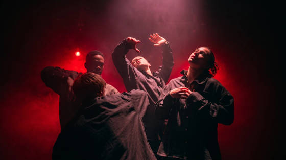 Dancers performing in a smoky, red-lit environment