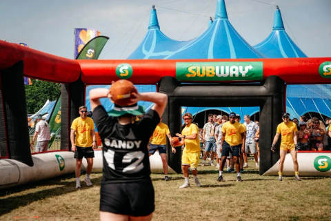 Participants playing a game at a festival with an inflatable Subway structure