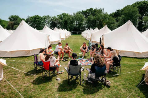 A group of people sitting in chairs around a game with bell tents in the background