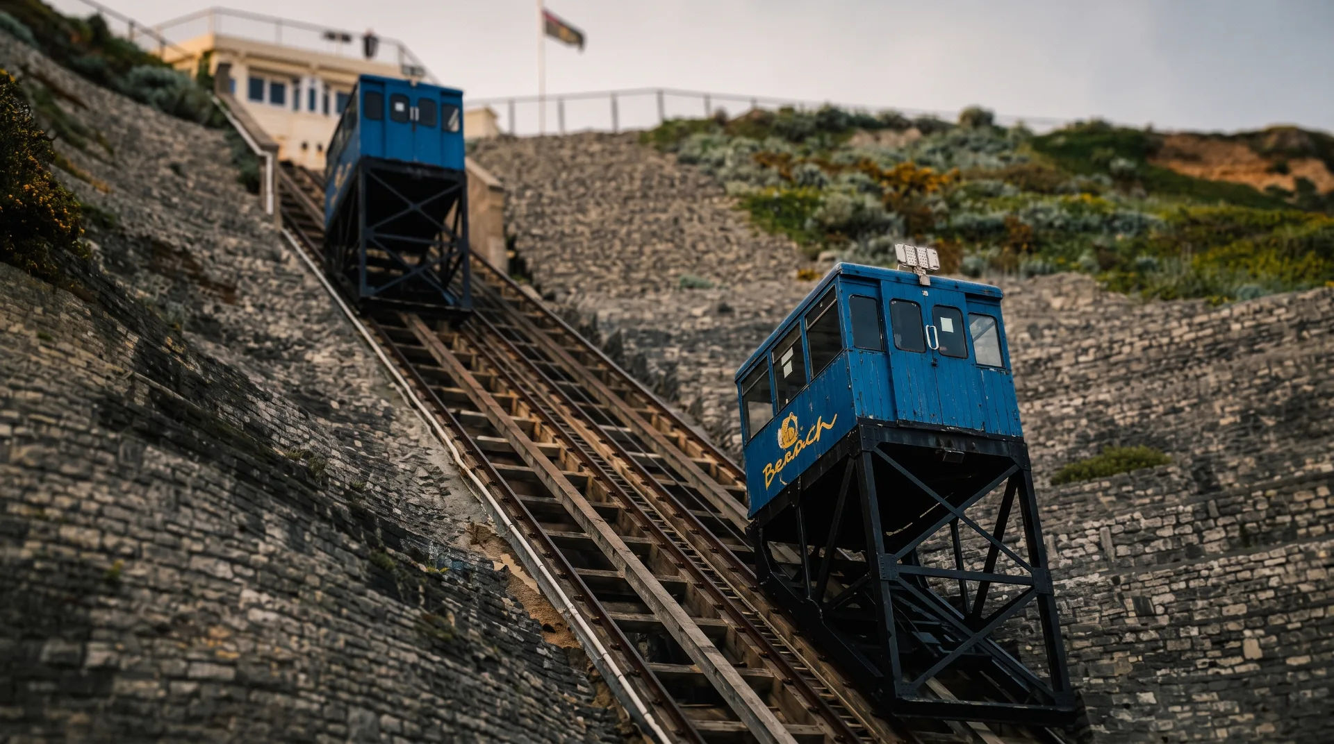 Two blue funicular railway cabins on a steep track with a stone hillside in the background