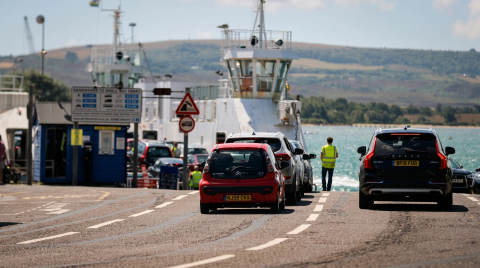 Cars lined up at Sandbanks ferry terminal with a ferry in the background