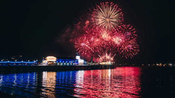 Colourful fireworks exploding over Bournemouth Pier with reflections in the water