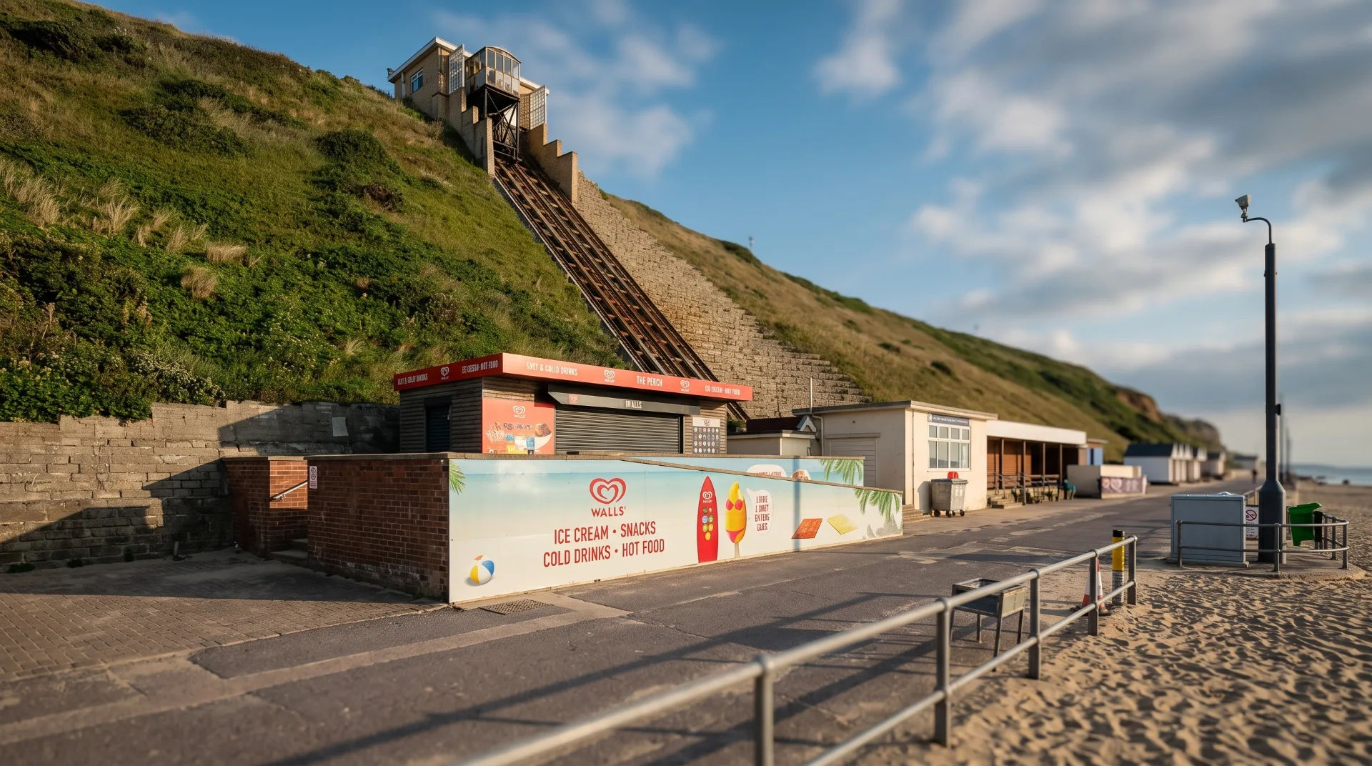 A beachfront kiosk selling ice cream and snacks, with a funicular railway leading up the hill.