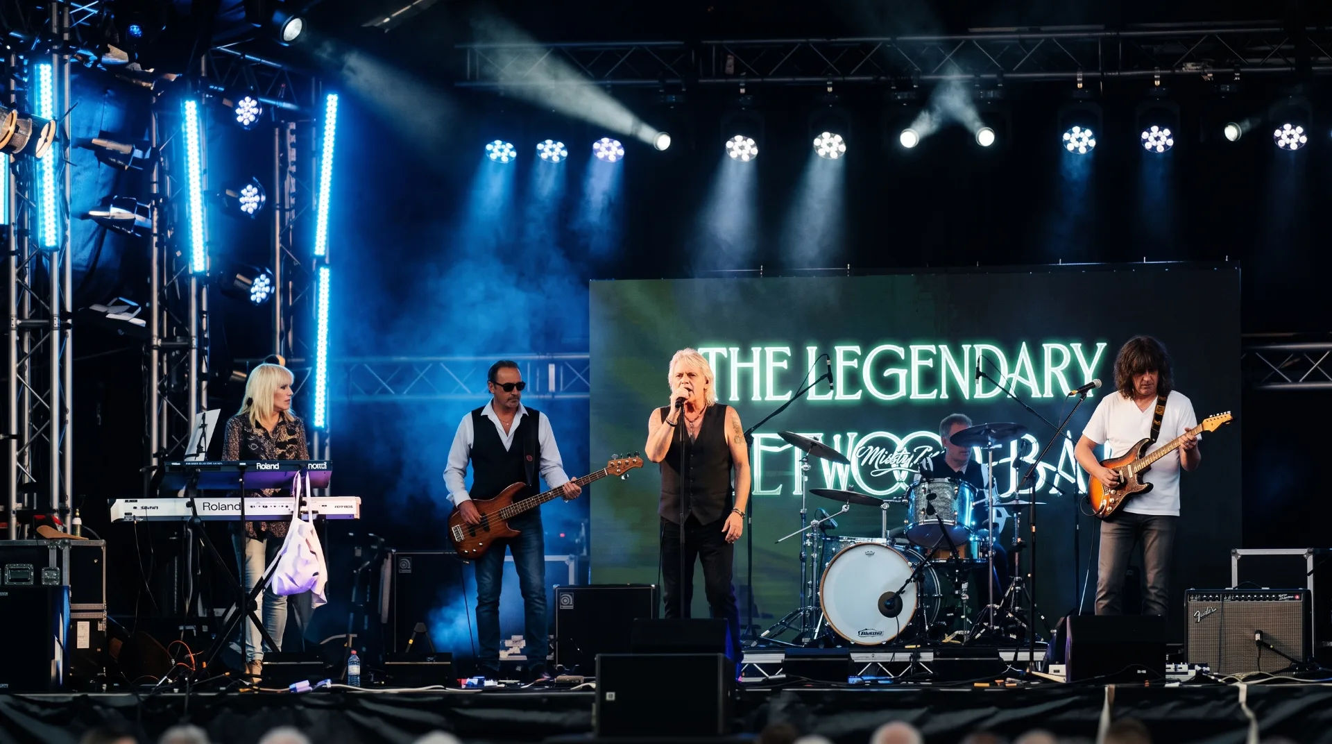 A tribute band performing on stage with instruments and bright lights at St Peter’s Church Poole
