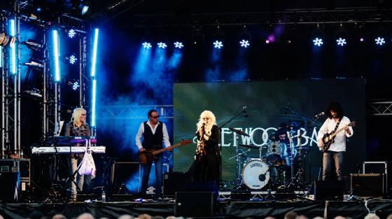 A band performing on stage with lights and a large screen behind them