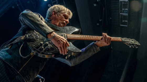 Musician in a leather jacket playing an electric guitar
