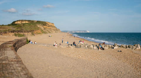People enjoying the beach with cliffs and the sea in the background