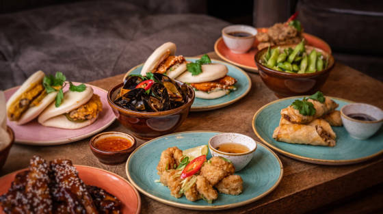 Variety of Asian dishes including bao buns, spring rolls, and edamame