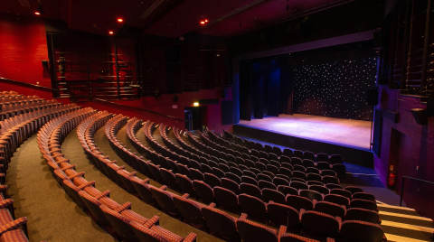 Theatre interior showing rows of seats and a stage with lights