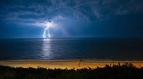 Lightning striking over the sea with dark clouds