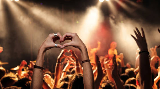 Hands forming heart shapes in a concert crowd