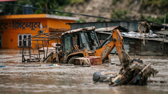 A JCB digger partially submerged in floodwater