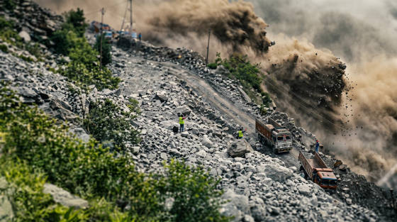 Workers in high-visibility vests at a rocky construction site