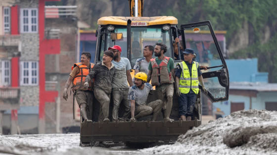 Workers on a tractor surrounded by mud and debris