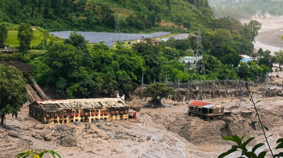 Ruined buildings surrounded by mud and greenery in a rural area