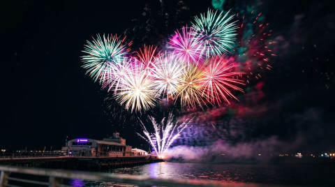Colourful fireworks bursting over a pier at night